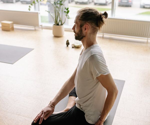 Person sitting in a calm meditative yoga pose by the window.
